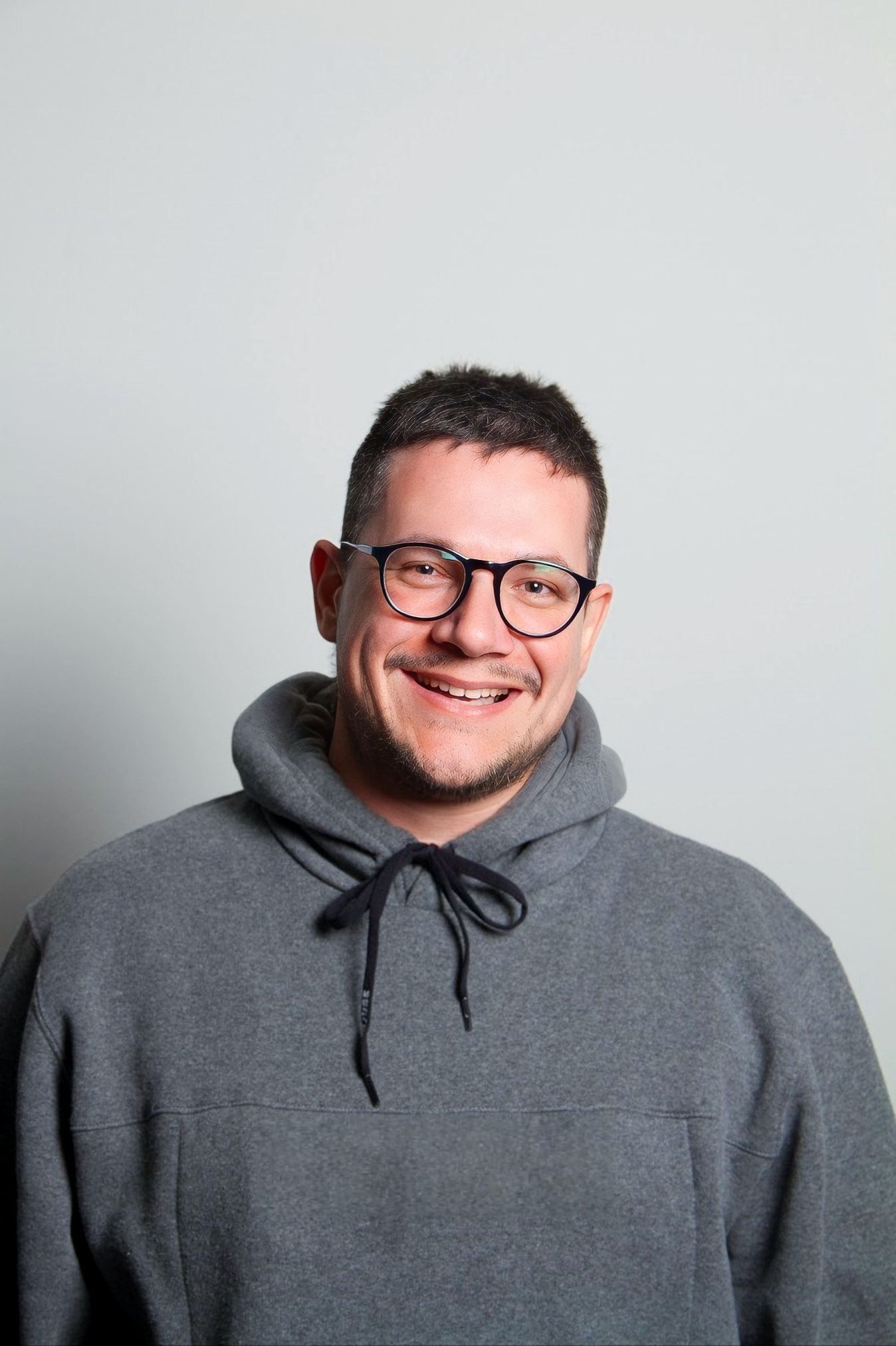 Jean Henrique sorrindo, usando óculos e moletom cinza